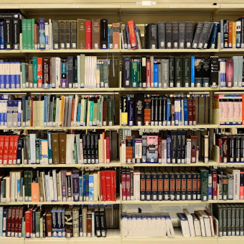 Scientific books of many colors line metal shelves, as in a school library. 